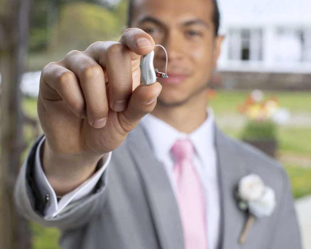Someone holding Phonak Audéo Lumity hearing aids in their hand.