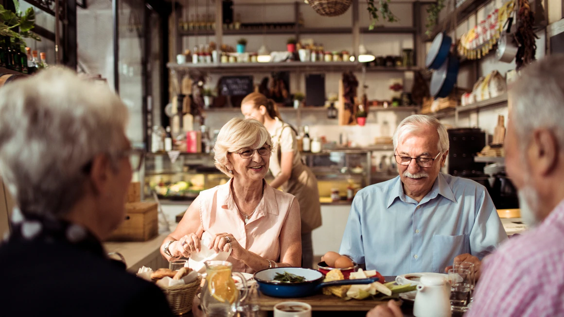 Close up of a group of seniors enjoying food in a restaurant.