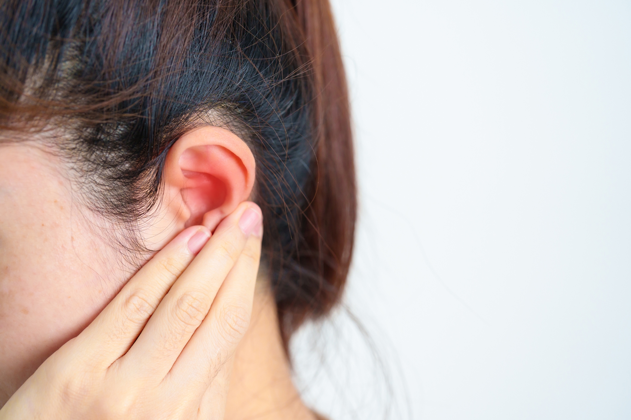 A woman holding her ear in pain.