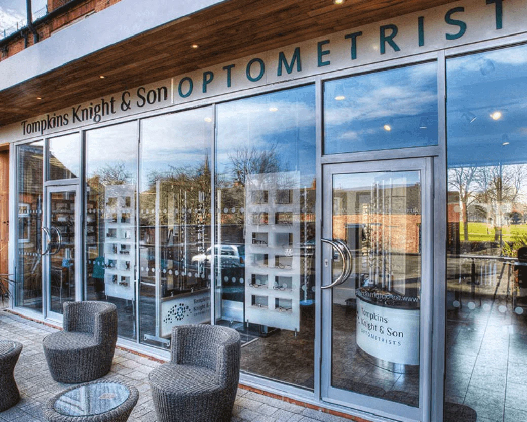 Tompkins Knight & Son Optometrists, outside the practice with a glass frontage and wicker seats