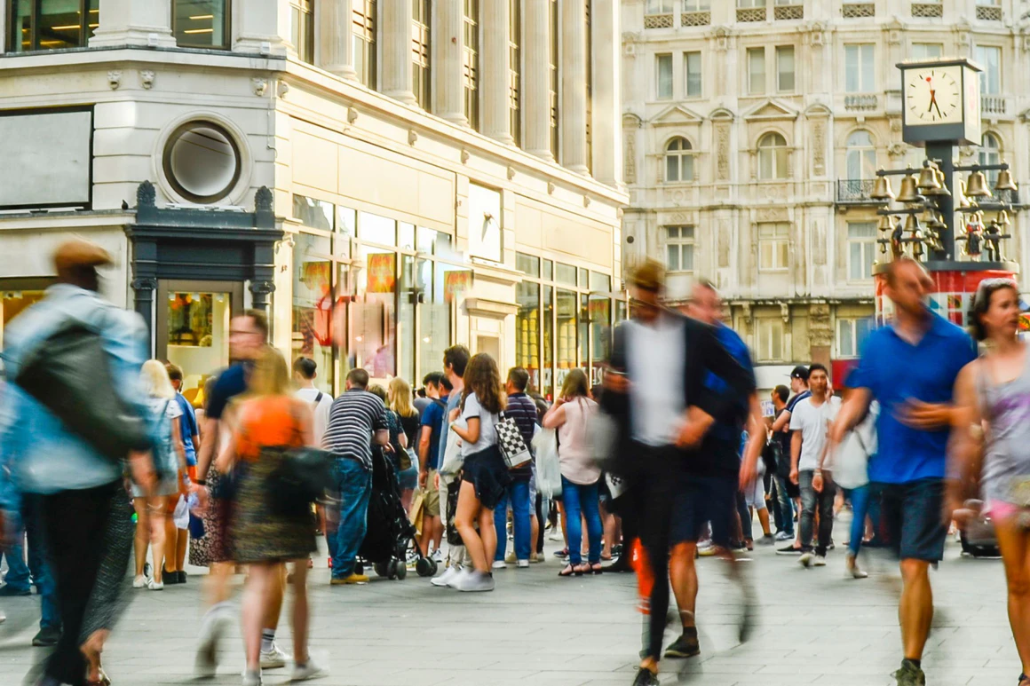 A bustling city street filled with pedestrians walking in various directions.