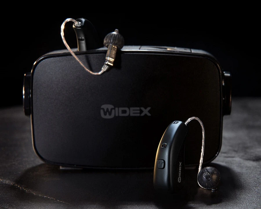 Widex hearing aids with their charging doc.