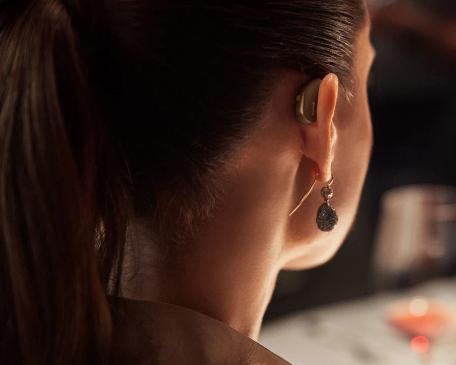 A woman wearing a widex hearing aid.